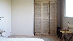 A bedroom with a bed, a wooden wardrobe, a chair, and a window. - Beautiful 4-bedroom house near Biarritz & Guéthary perfect for relaxing getaways (Arbonne)