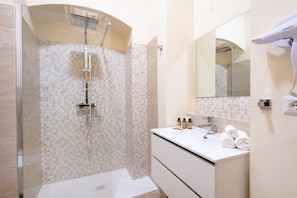 A modern bathroom with a glass-enclosed shower, a white vanity with a mirror, and neatly rolled towels. - City Hub 5 | Elegant Historic Apartment in Central Bari  (Bari)