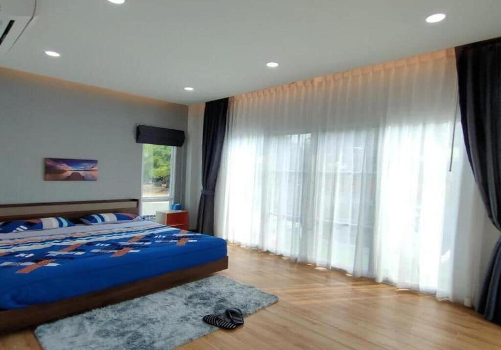 Ein Schlafzimmer mit einem Bett, einem Fernseher und einem Fenster mit Vorhängen.