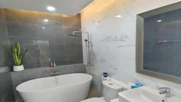 Un baño moderno con una bañera independiente, inodoro y lavamanos.