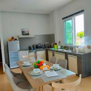 Una cocina moderna con comedor, refrigerador, microondas y ventana que proporciona luz natural.