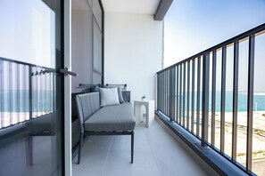 A balcony with a sofa, a small table, and a view of the sea.