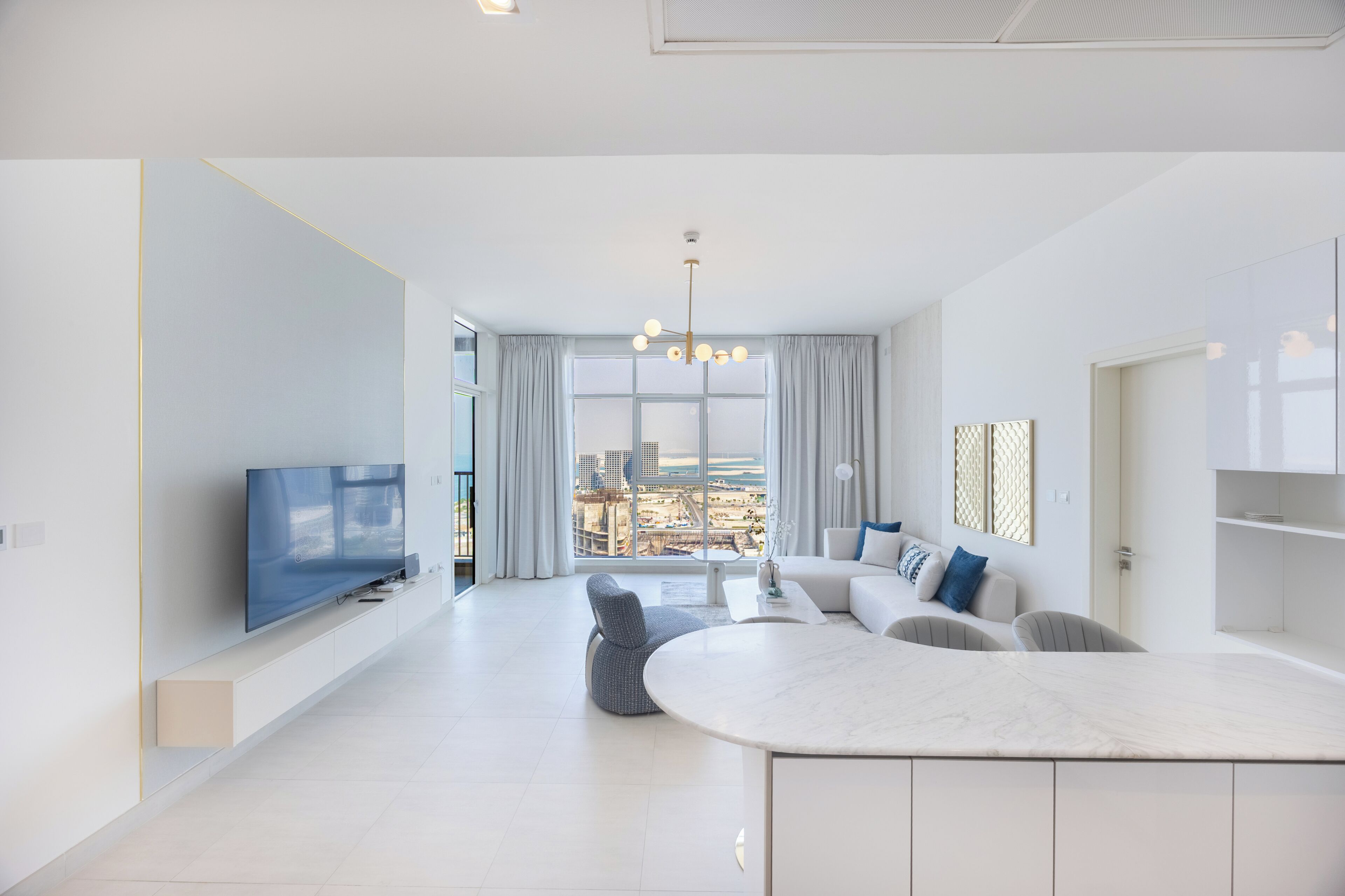 Ein modernes Wohnzimmer mit Flachbildfernseher, einer Sofagarnitur, einem Couchtisch und einem großen Fenster mit Blick auf die Stadtlandschaft.