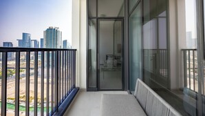 A balcony with a city view, a glass door, and a seating area. - Bloomfields 2BR in The Bridges - Reem (Abu Dhabi)