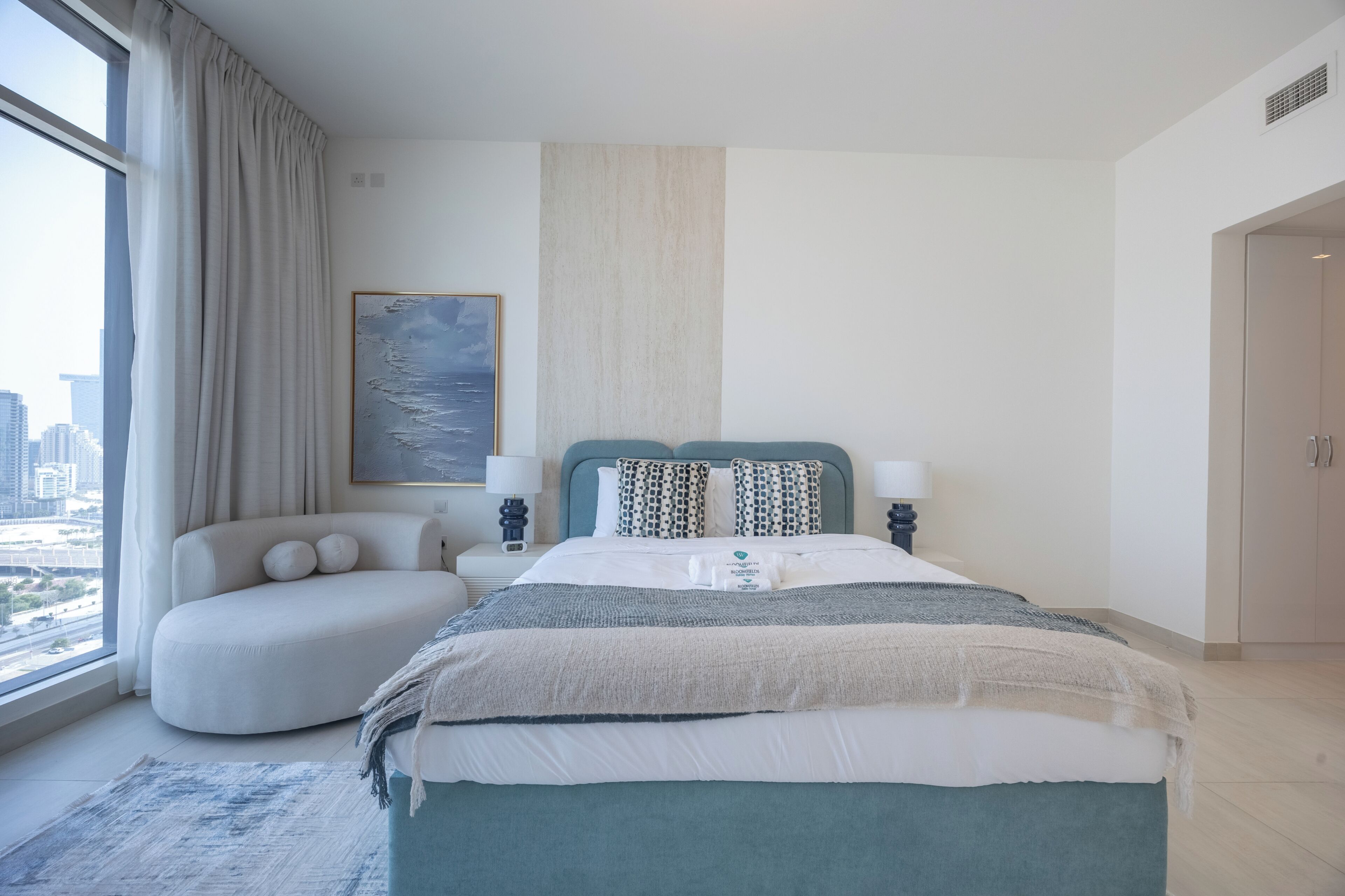 A modern bedroom with a large bed, a sofa, and a view of the city.