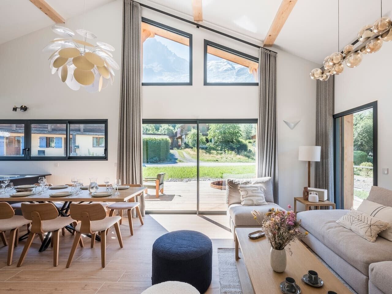 Een moderne woonkamer met een eethoek, grote ramen en uitzicht op de omgeving.
