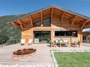 A wooden cabin with a deck, outdoor seating, and a hot tub. - Chalet 4BR – Nordic bath – parking and garage (Chamonix)