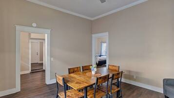 A dining area with a wooden table and chairs, a ceiling fan, and a view into another room.