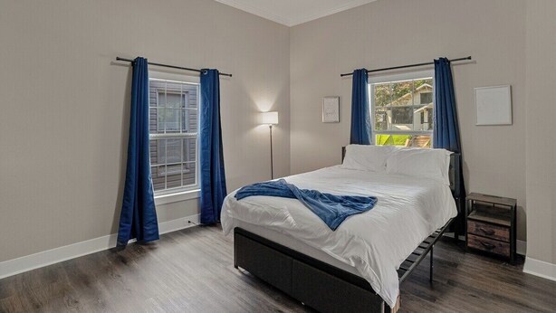 A bedroom with a bed, a nightstand, a lamp, and a window with curtains. - 3 bedroom, 1.5 bathroom single family home in the Historic Highland Neighborhood (Shreveport)