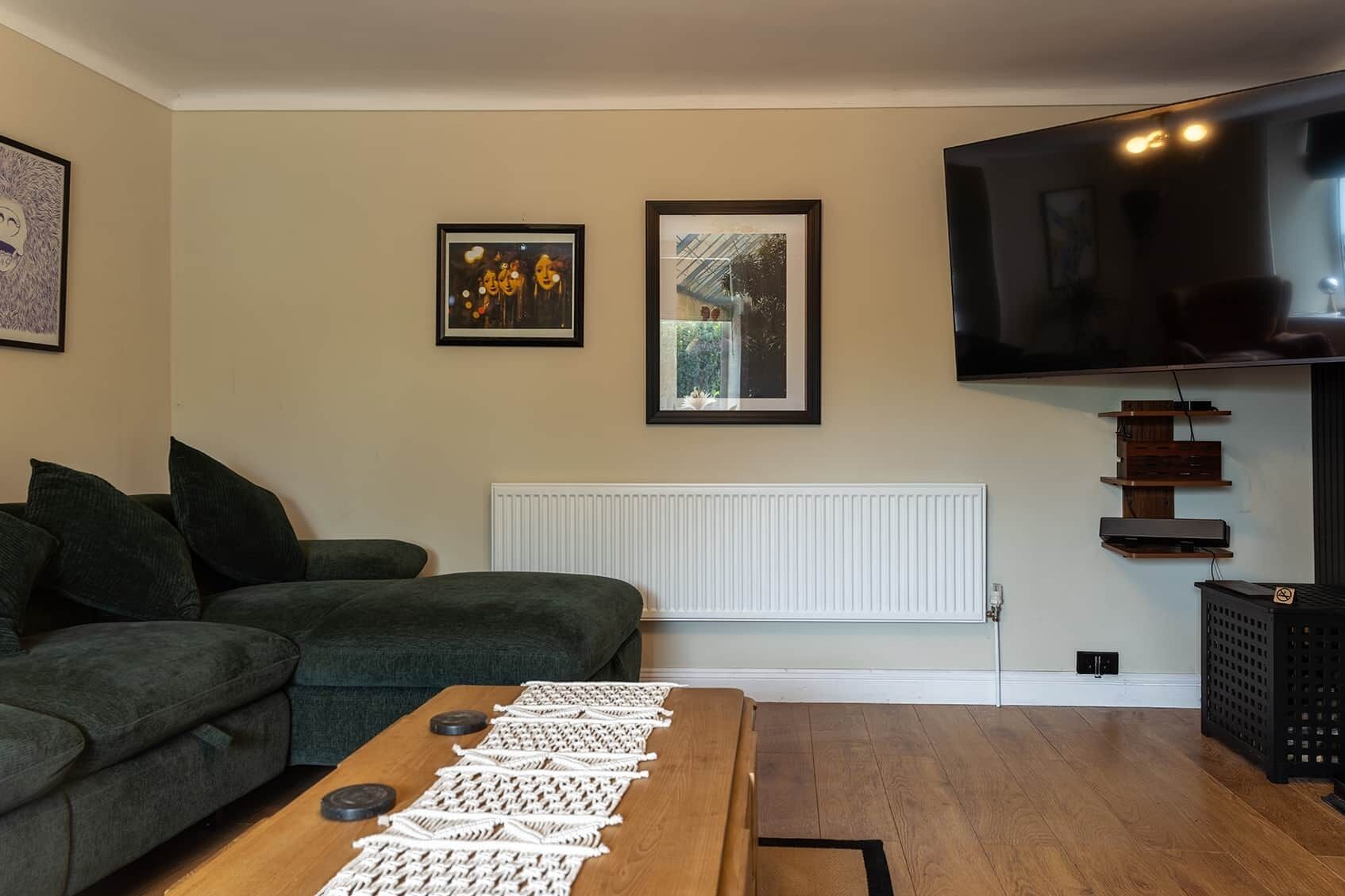 Una sala de estar con un sofá, una mesa de centro con posavasos, un televisor y cuadros en la pared.