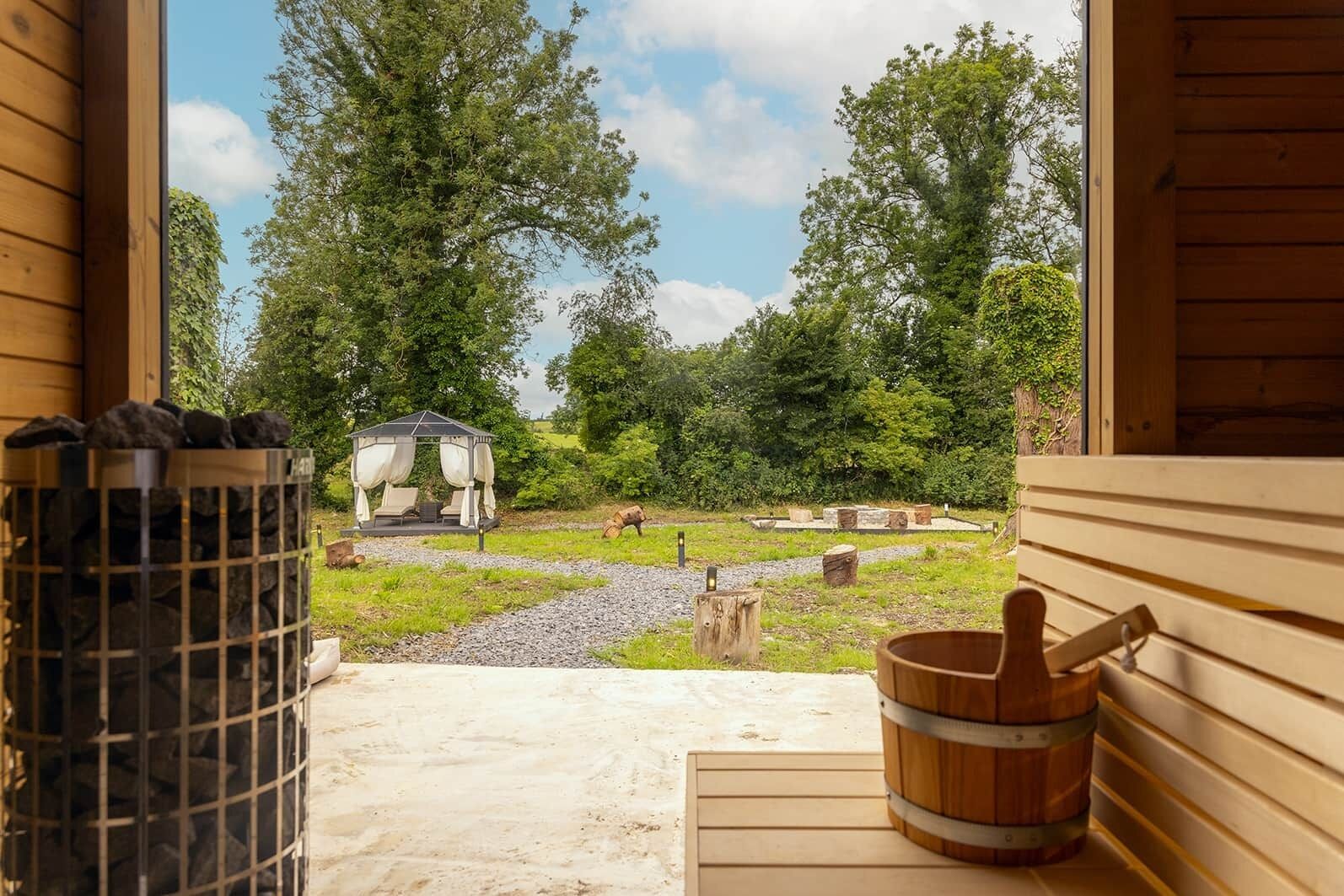 A wooden cabin with a stone fire pit and a wooden tub.