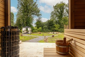 A wooden cabin with a stone fire pit and a wooden tub.