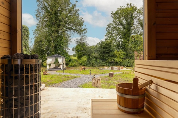 A wooden cabin with a stone fire pit and a wooden tub.