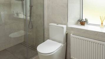 A modern bathroom with a glass-enclosed shower, a white toilet, and a window with a view.