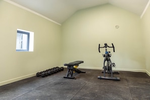 A gym with exercise equipment, a bench, and dumbbells.