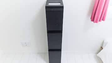 Un contenedor de almacenamiento negro con ruedas en una habitación con paredes y piso blancos.