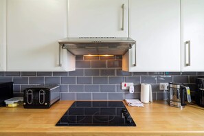 Eine moderne Küche mit einem schwarzen Induktionskochfeld, einem Toaster, einem Wasserkocher und einer Kaffeemaschine.