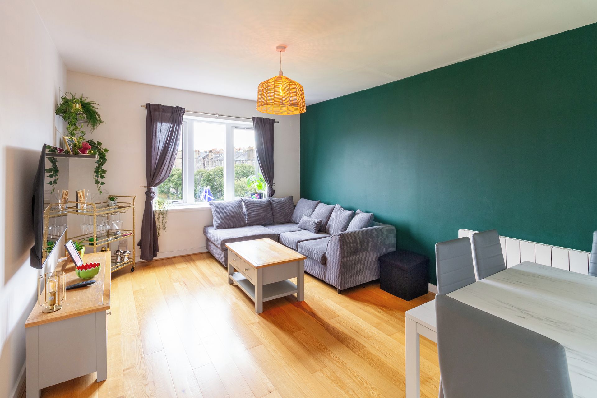 A modern living room with a sofa, a coffee table, a TV, and a dining area with a table and chairs.