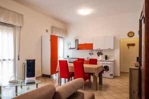 A compact living space with a dining area, kitchenette, and a washing machine. - GuestHost - Bright Apartment in Piombino (Piombino)