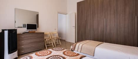 A bedroom with a bed, a dresser, a television, and a wardrobe.