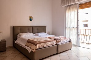 Ein Schlafzimmer mit einem Bett, einem Nachttisch, einer Wanddekoration und Blick durch eine Schiebetür.