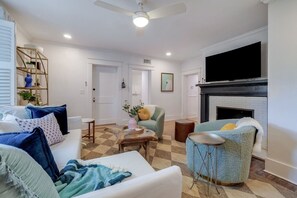 A living room with a fireplace, a television, and a ceiling fan. - Midnight Garden A - Refined Stay Neighboring the Mercer Williams House on Monterey Square (Savannah)
