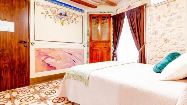 Ein Schlafzimmer mit einem Bett, einer Holztür, einer Steinsandsteinwand und einem gemusterten Boden.