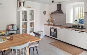 Eine moderne Küche mit weißen Schränken, einem Holztisch und einem eingebauten Backofen.