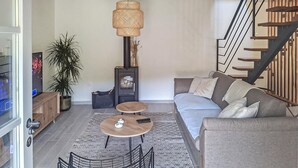 A modern living room with a sofa, two small tables, a decorative lamp, a staircase, and a potted plant. - Lovely home in Kucice with house a panoramic view (Kucice)