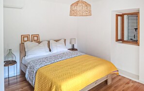 Ein Schlafzimmer mit Bett, Nachttischen, einer Pendelleuchte und einem Fenster.