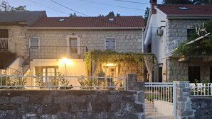 A stone building with a tiled roof, a gated entrance, and a lit exterior light. - Lovely home in Kucice with house a panoramic view (Kucice)