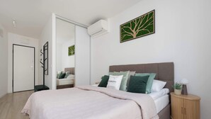 A bedroom with a bed, bedside table, and a wall-mounted air conditioner. - Stylish Studios with Balconies | Close to the Underground | City Centre (Warszawa)