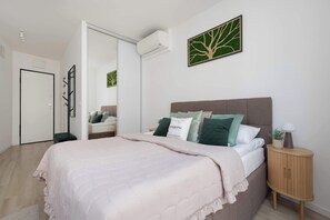 A bedroom with a bed, bedside table, and a wall-mounted air conditioner. - Stylish Studios with Balconies | Close to the Underground | City Centre (Warszawa)