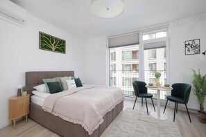 A modern bedroom with a bed, bedside table, and a view of the city through large windows. - Stylish Studios with Balconies | Close to the Underground | City Centre (Warszawa)