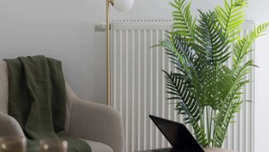 A minimalist living space with a radiator, a green plant, a laptop on a small table, and a framed abstract artwork on the wall. - Stylish Studios with Balconies | Close to the Underground | City Centre (Warszawa)