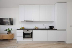 A modern kitchen with white cabinetry, a built-in oven, and a coffee maker. - Stylish Studios with Balconies | Close to the Underground | City Centre (Warszawa)