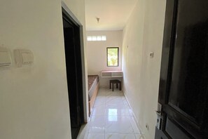 A hallway with a bed, a window, and a door. - Podomoro Residence Syariah (Sleman)