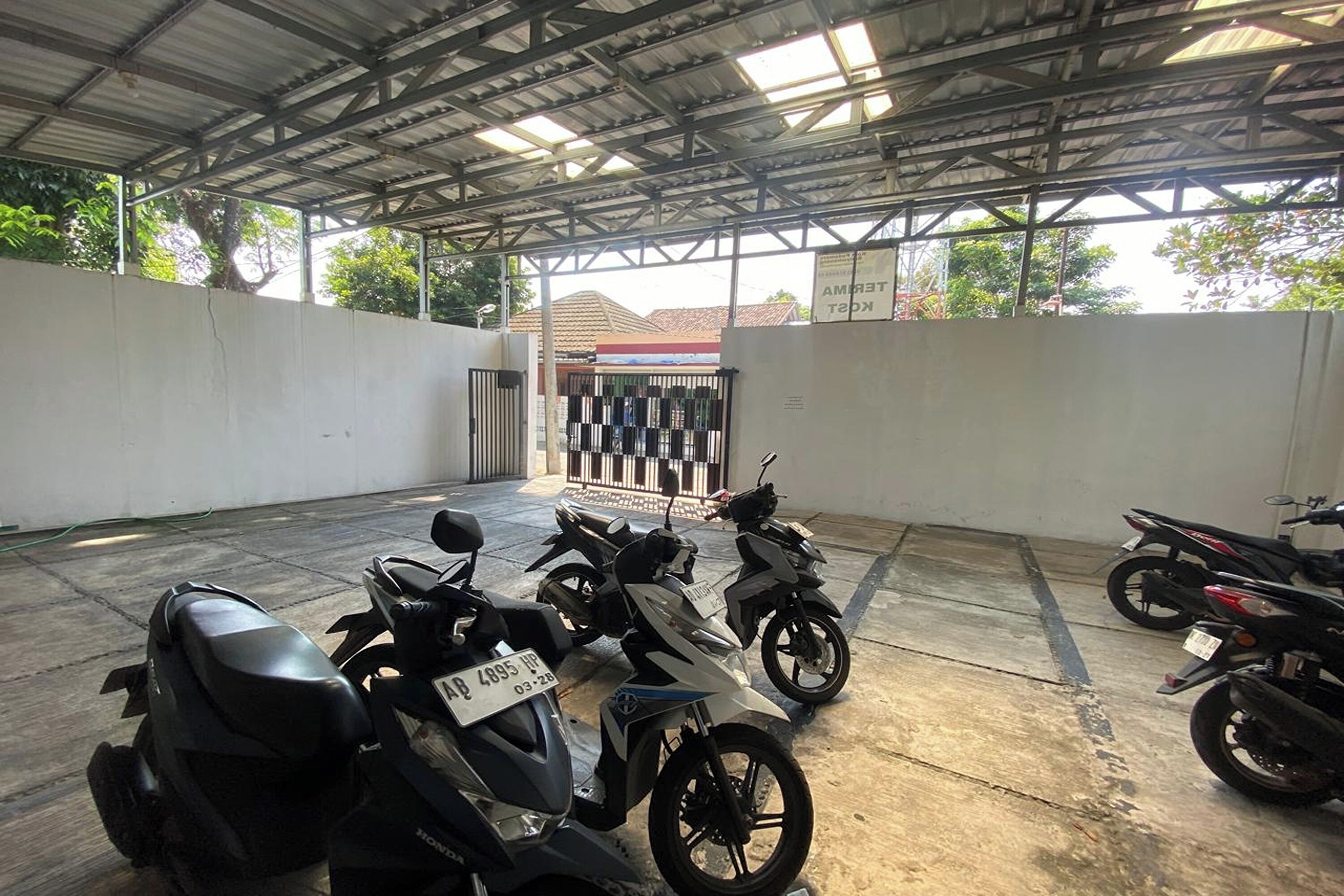 A covered parking area with several motorcycles parked.