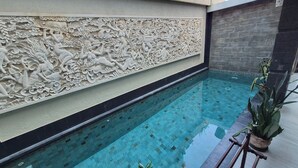 Une piscine agrémentée d’un mur décoratif orné de sculptures complexes.