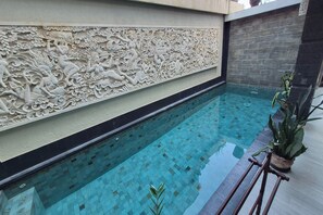 A swimming pool with a decorative wall featuring intricate carvings.