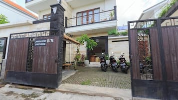 Una entrada con portón a una casa de huéspedes, con un letrero que indica que pertenece a la propiedad Canggu Spirit.