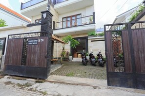 Una entrada con portón a una casa de huéspedes, con un letrero que indica que pertenece a la propiedad Canggu Spirit.