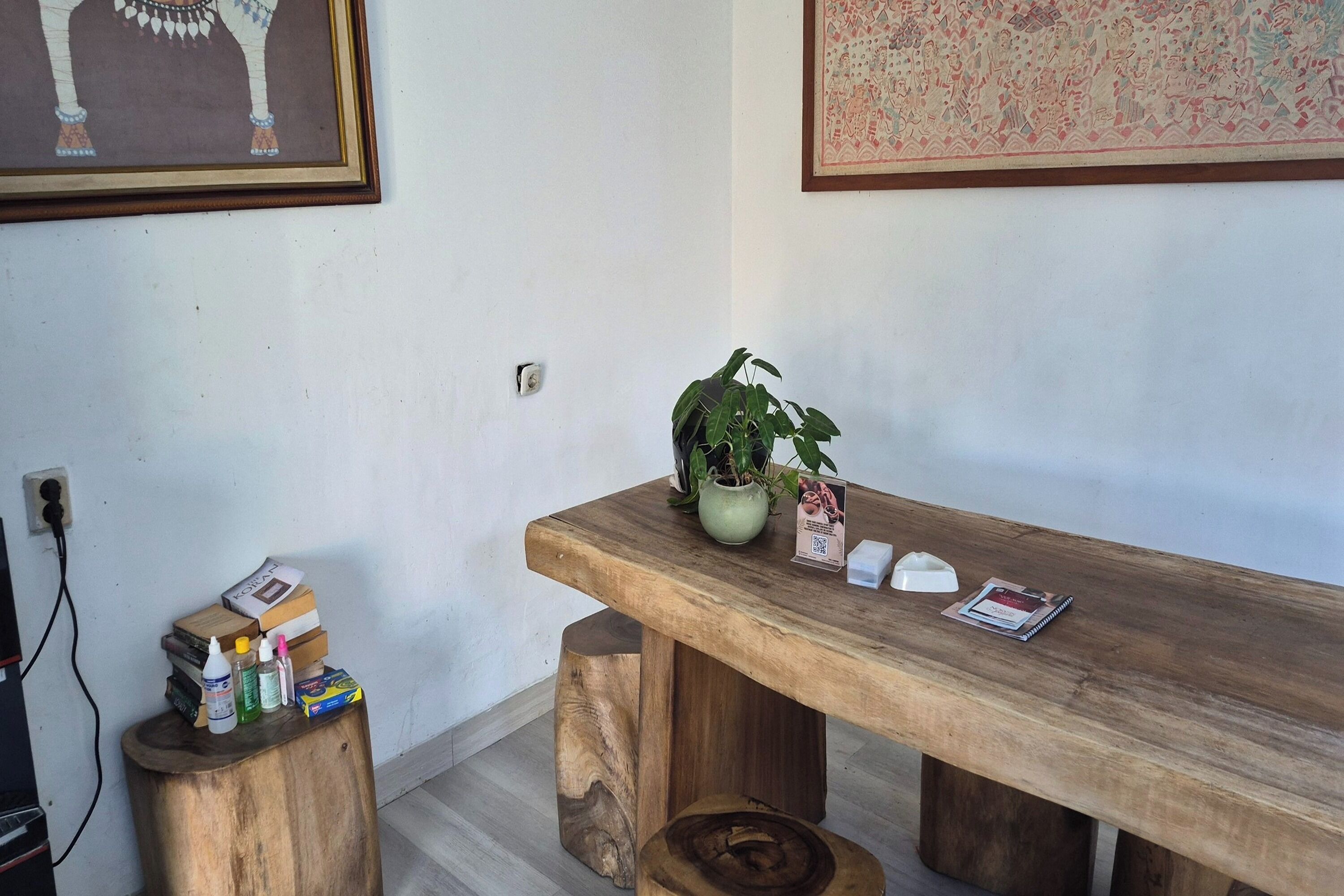 Una mesa de madera con una planta en maceta, libros y un cartel con un código QR.