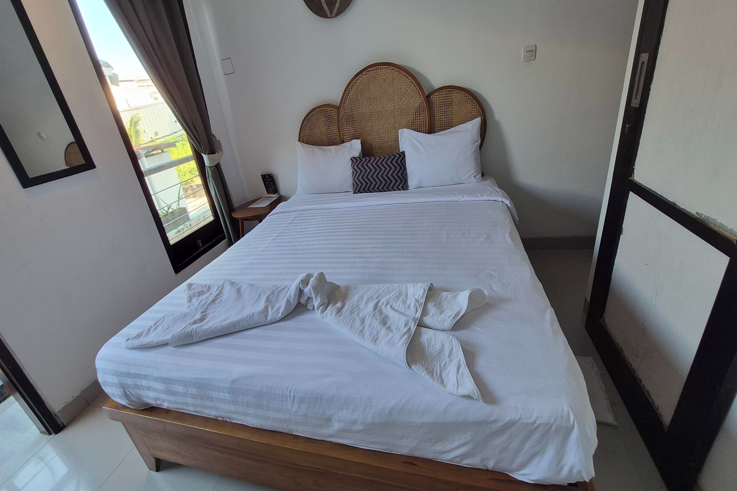 Una cama bien hecha con sábanas blancas y un cabecero de madera.