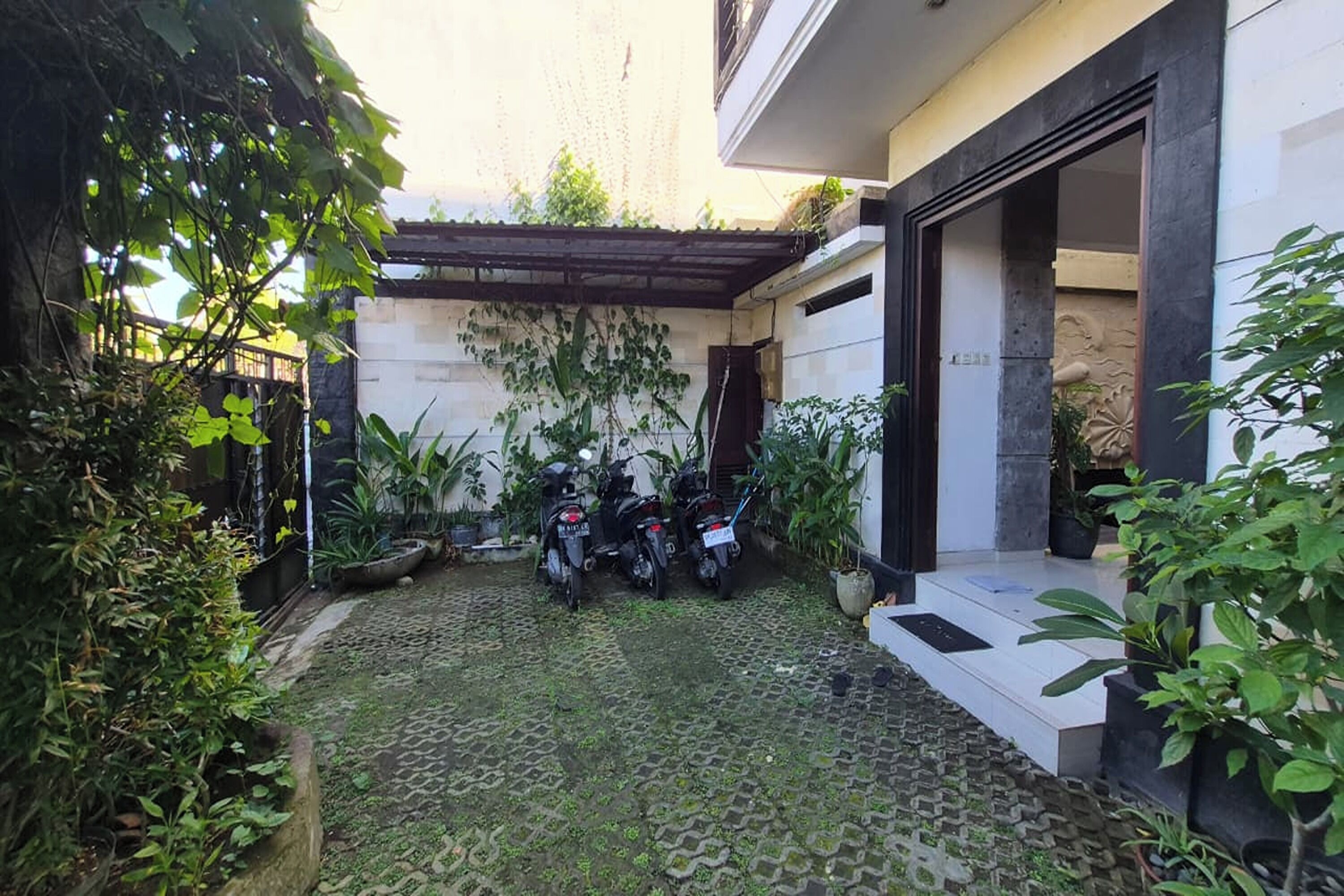 Ein Innenhof mit befestigtem Boden, Blumentöpfen und zwei abgestellten Motorrädern.