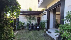 Une cour avec une zone dallée, des plantes en pot et deux motos garées.