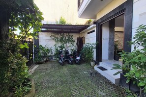 A courtyard with a paved area, potted plants, and two motorcycles parked.