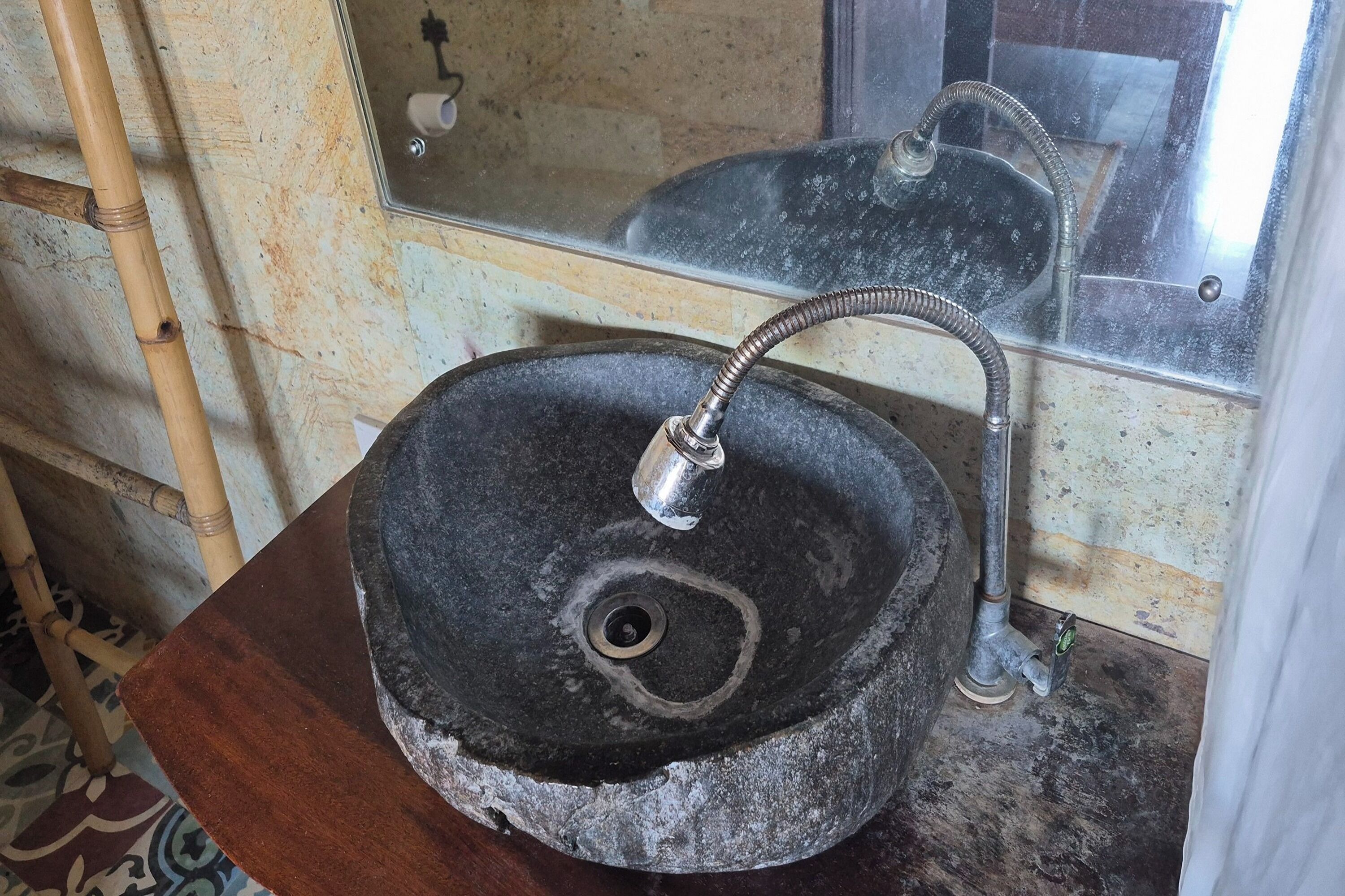 Un lavamanos de piedra con un grifo sobre una encimera de madera.