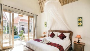 A bedroom with a large bed, a canopy, two bedside lamps, and a view of a pool and outdoor area. - The Box Paradise Bungalow (Penida Island)