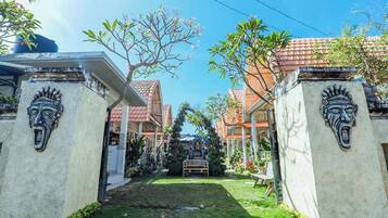 A residential area with houses featuring traditional architecture, a well-maintained lawn, and a clear sky.